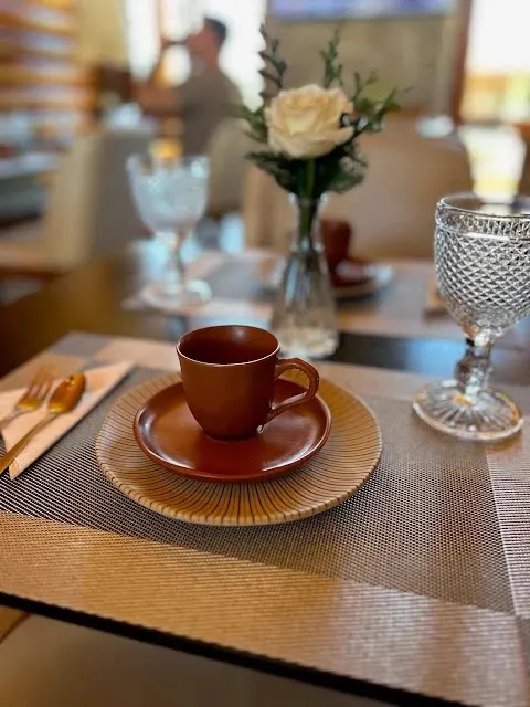 Mesa posta do café da manhã com xícara e flores no salão da pousada em Monte Verde MG
