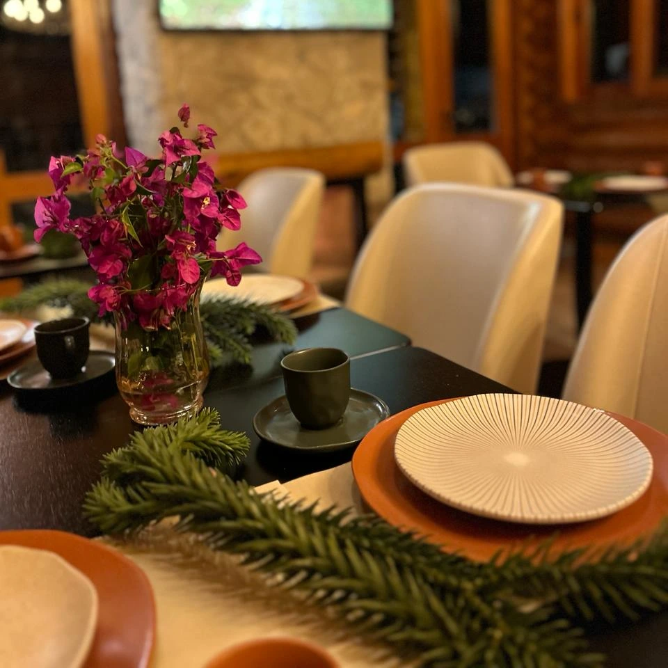 Mesa do café da manhã colonial da Pousada Maple Monte Verde com bolos, pães e frutas